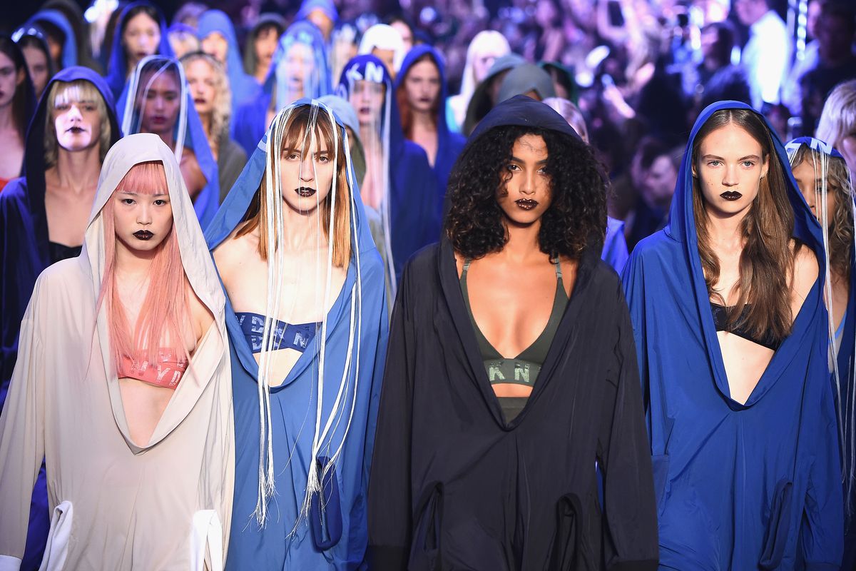 An army of models walk the runway wearing loose hoodies in blue, black, and white.