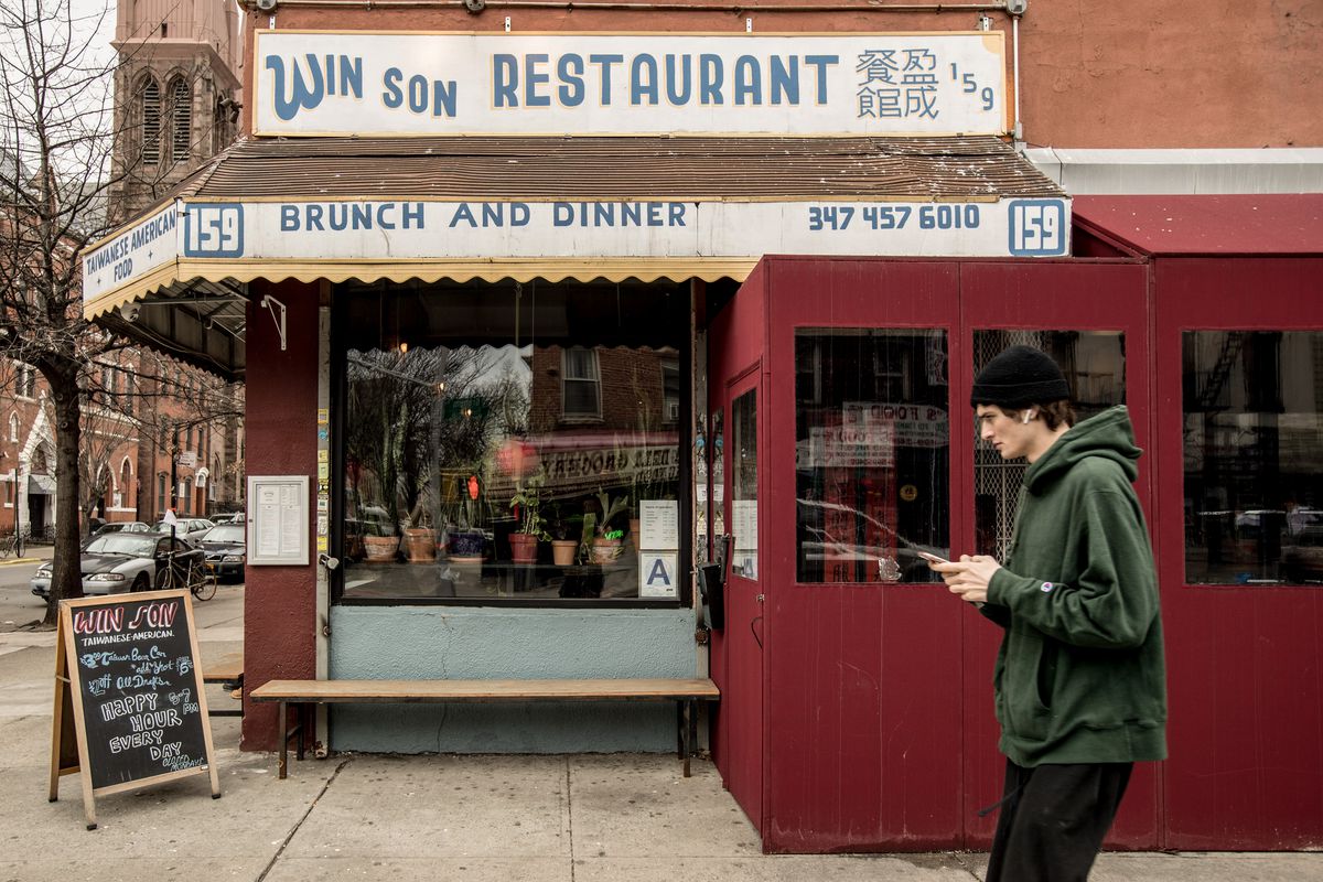 The old-school, deli-like exterior of Win Son, with a pedestrian crossing in front of the restaurant
