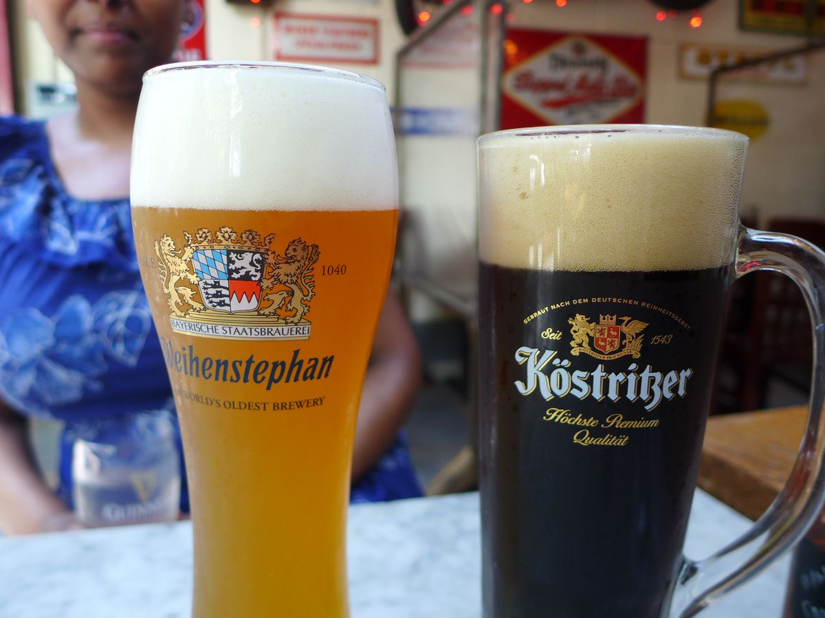 Two German beers in fluted glasses with the logos of the beer companies.