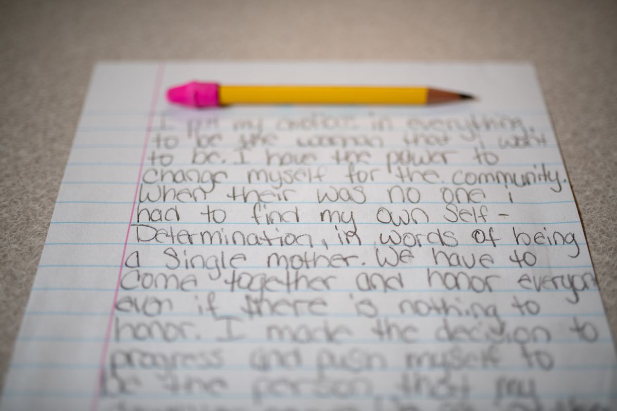 A pencil with a pink eraser sits atop an essay written on lined paper.