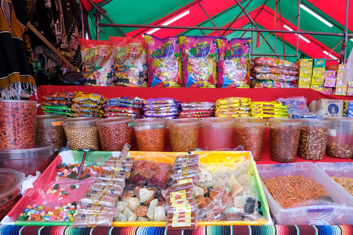 Rows of candy on display in plastic tubs or large bags in a market-like setting.