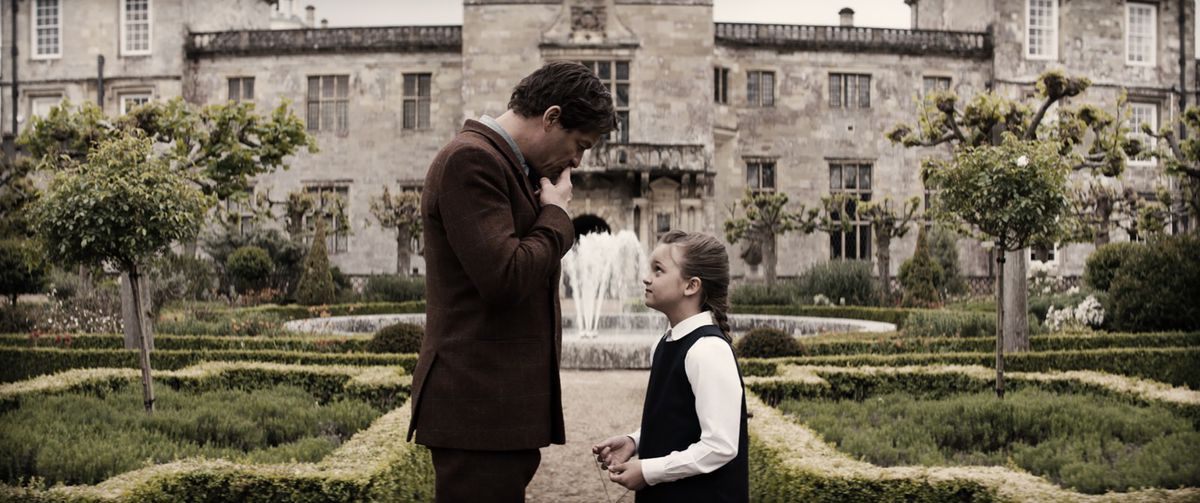 Tomb Raider movie - flashback with Lord Richard Croft (Dominic West) and young Lara Croft (Maisy de Freitas) in front of the family mansion