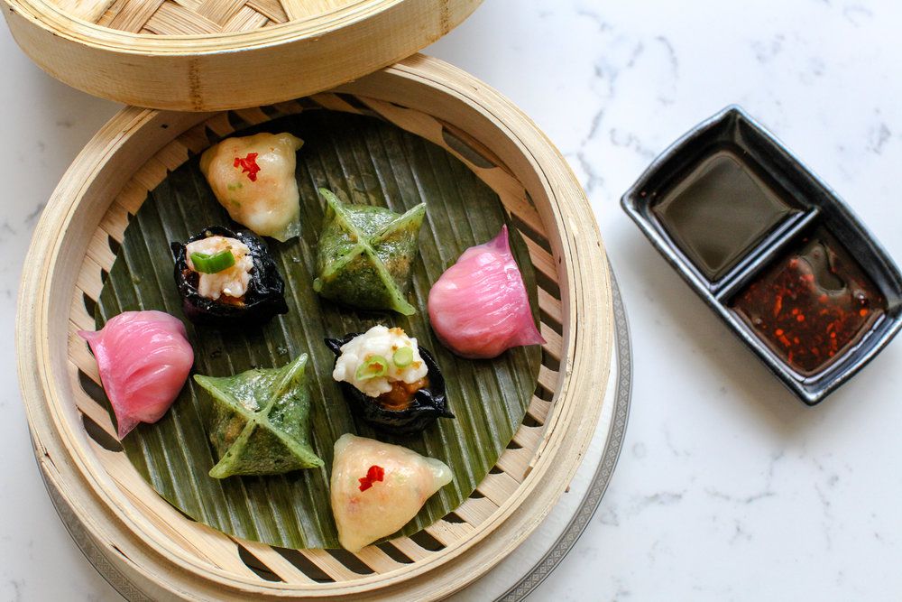An array of colorful dumplings in a bamboo basket.