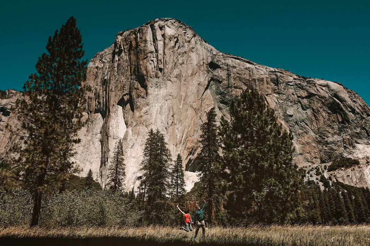 Couple jumping by El Capitan in the meadow. Yosemite...