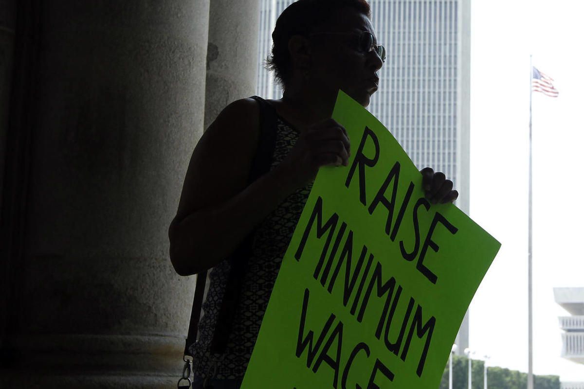 Wendy Brown of Schenectady, N.Y., holds a sign before an Occupy Albany rally pushing for a raise in the state's minimum wage at the Capitol in Albany N.Y., on Tuesday, May 29, 2012.