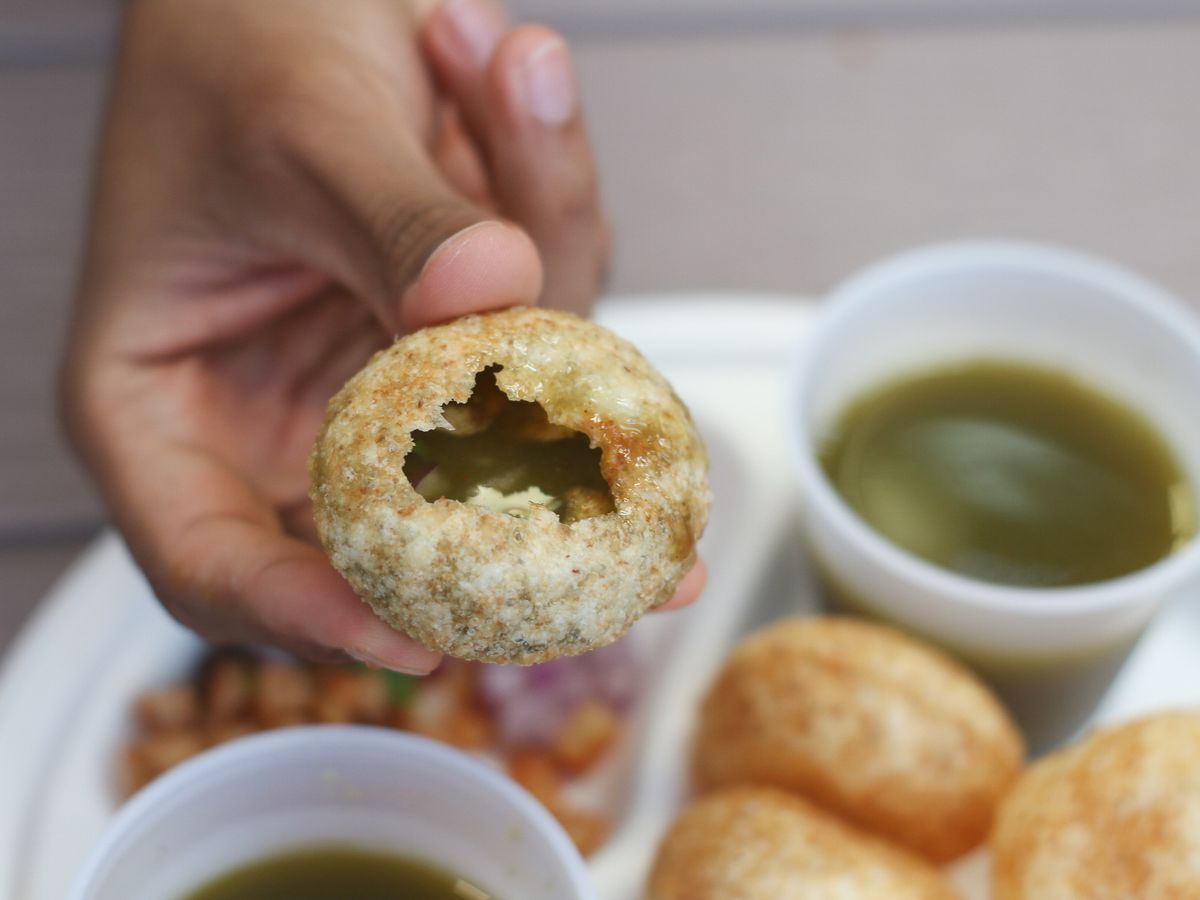 A hand holding a filled pani puri 