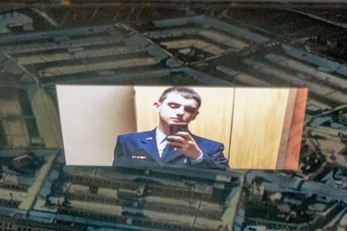 An image of a man in a uniform holding a phone reflected on the Pentagon building.