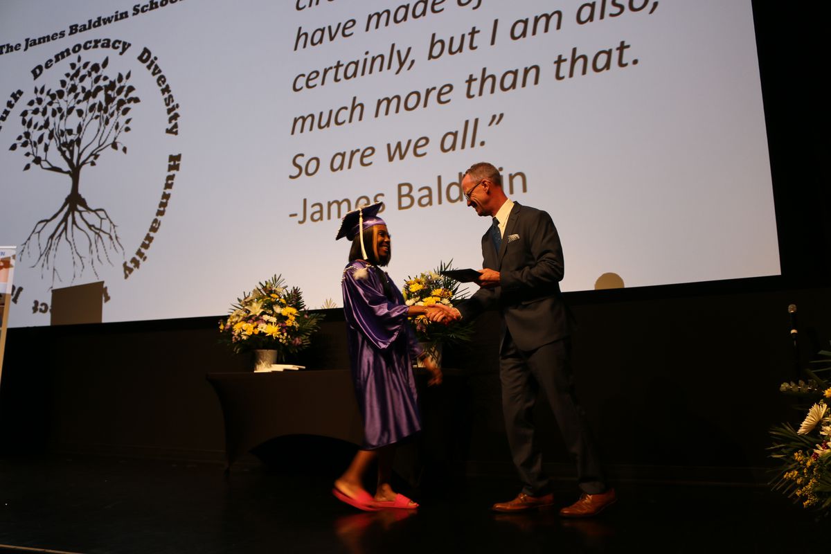 A student receives her diploma from Principal Brady Smith during the James Baldwin School's graduation in June 2019.