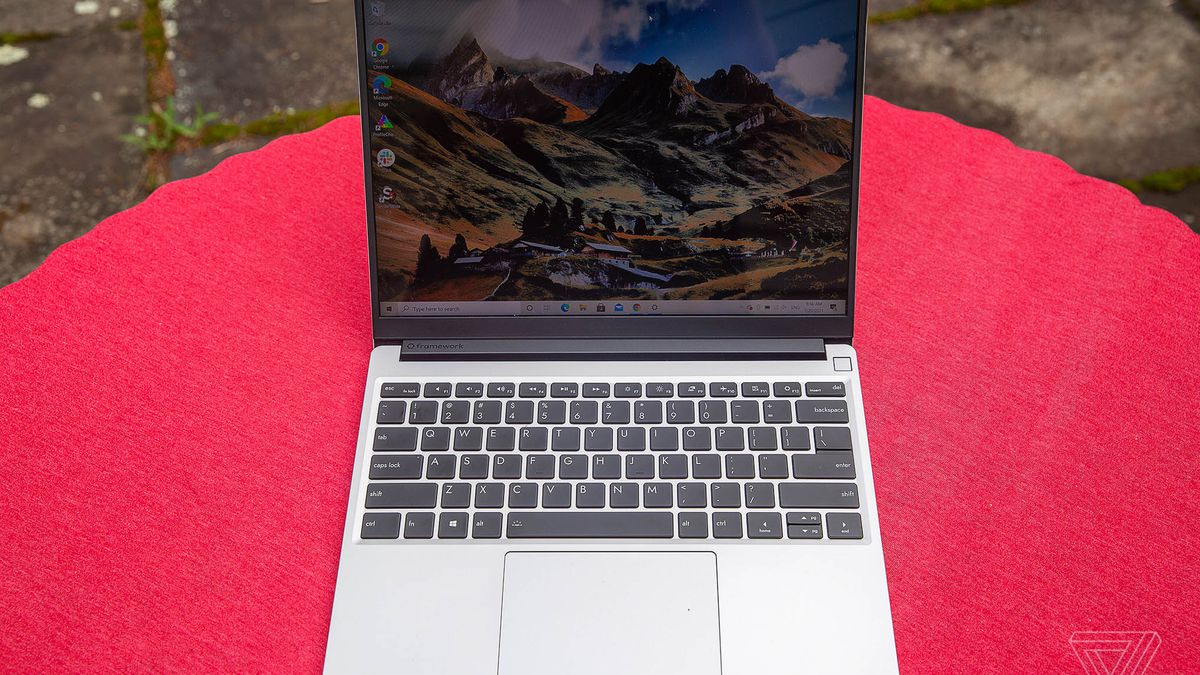 The Framework Laptop outdoors on a red tablecloth, seen from above, open. The screen displays a mountainous landscape.