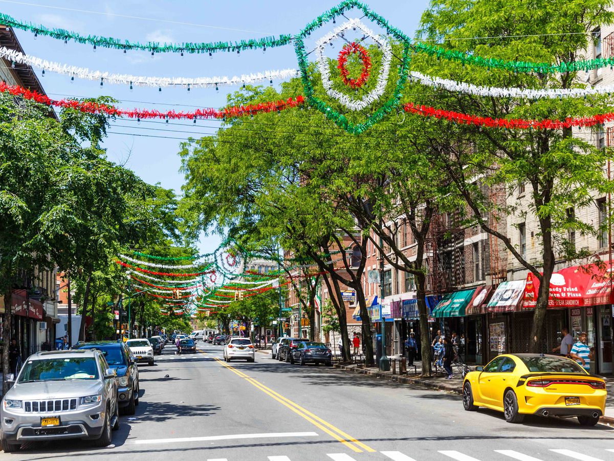 Arthur Avenue is shown with a red, white, a green banner over a city street.