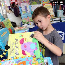 Tyler Marion, age 5, looks at books at the Usborne Books tent at the KSL Family Book Festival at The Gateway in Salt Lake City on Saturday, June 15, 2013.