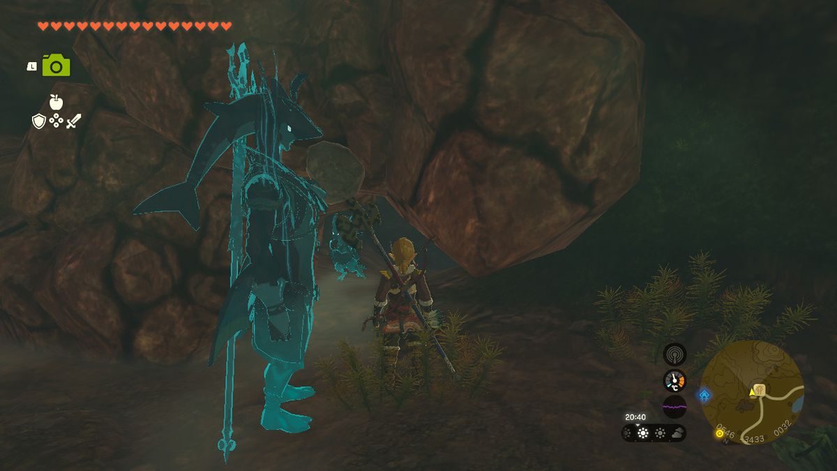 Link stands next to a cracked wall in a cave at the bottom of a well in Zelda Tears of the Kingdom.