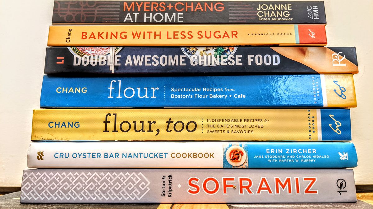 A stack of eight cookbooks, spines facing the camera, with titles including Sweet Basil, Soframiz, Double Awesome Chinese Food, and more.