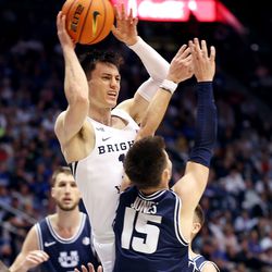 Brigham Young Cougars guard Alex Barcello (13) jumps and passes over Utah State Aggies guard Rylan Jones (15) as BYU and Utah State play an NCAA basketball game in Provo at the Marriott Center on Wednesday, Dec. 8, 2021. BYU won 82-71.