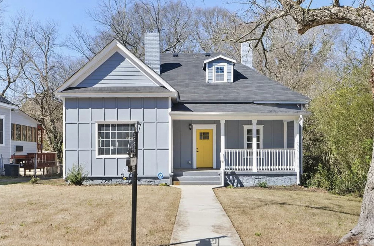 Slate gray house with yellow door and covered porch.