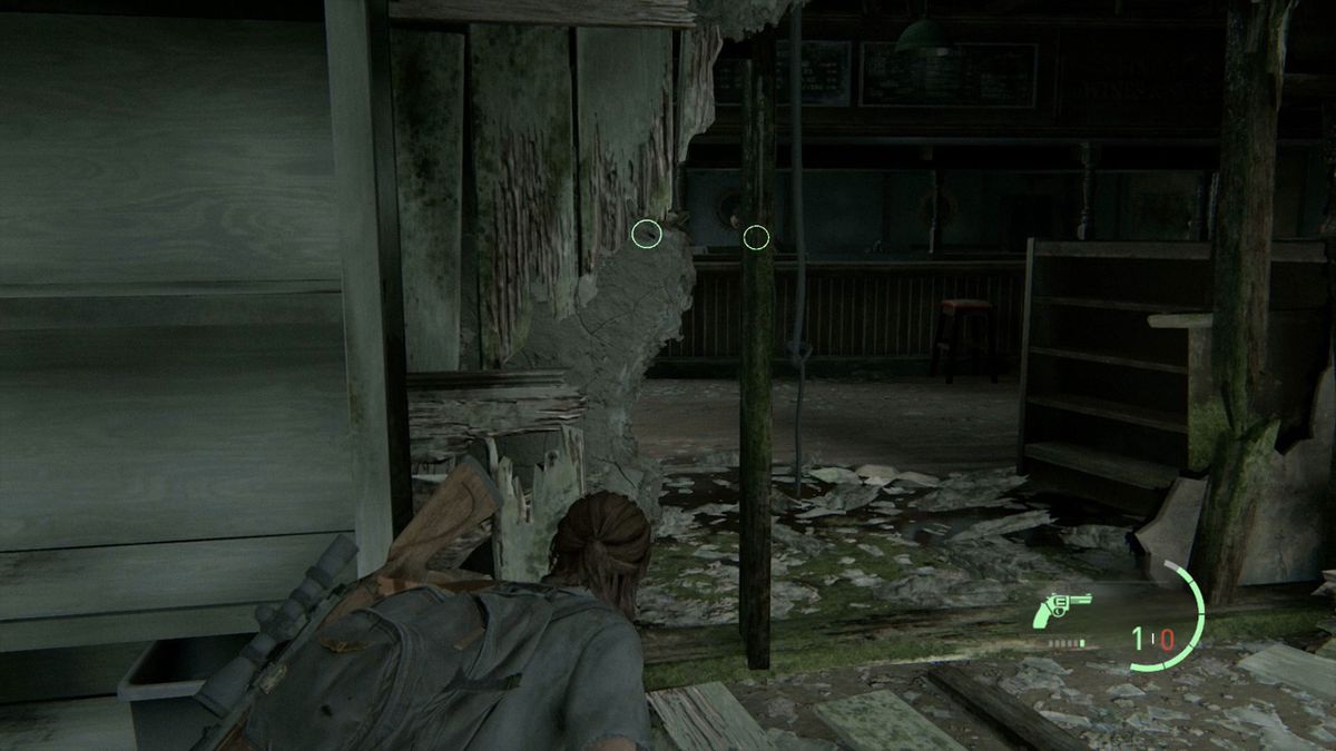 Ellie hides behind cover while looking for items or collectibles in The Last of Us Part 2