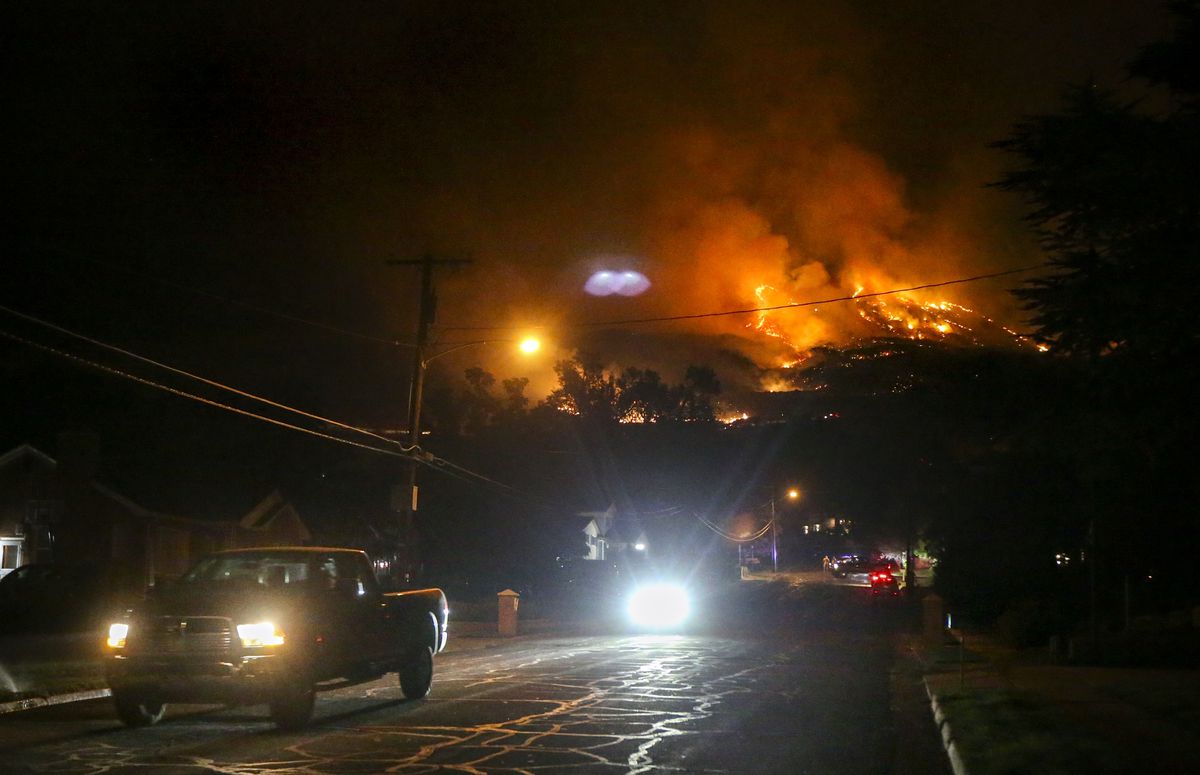 Evacuees and interested civilians drive down East Pages Lane as a fire burns on the hill East of Centerville early on the morning of Friday, Aug. 30, 2019. 27 homes have been evacuated in the Centerville area as of 5 AM.