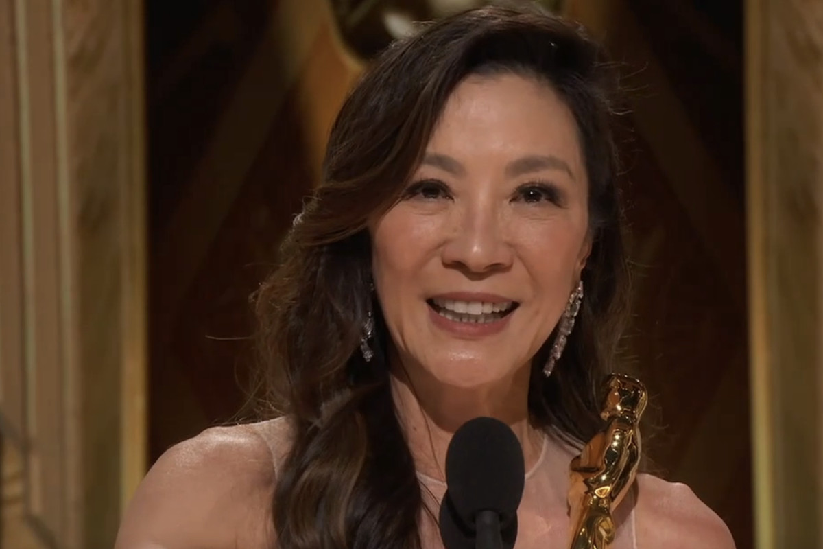 Michelle Yeoh smiling as she holds her Oscar while giving her speech