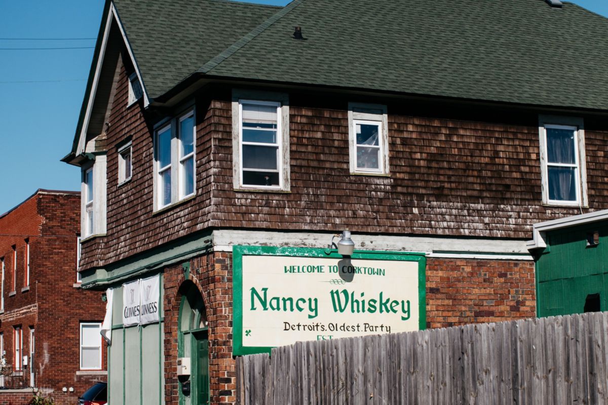 The exterior of Nancy Whiskey’s is covered in wood cladding with a green roof on a sunny, cloudless day.