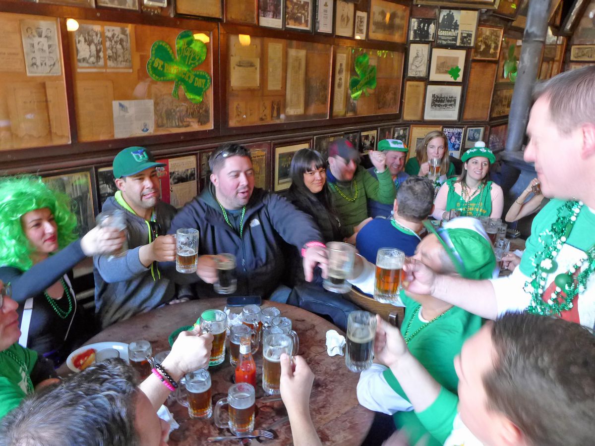 Two tablefuls of revelers, some with green clothing and hair.