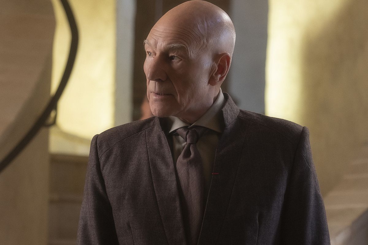 Patrick Stewart as Star Trek’s Jean-Luc Picard wears a brown civilian suit and brown tie.