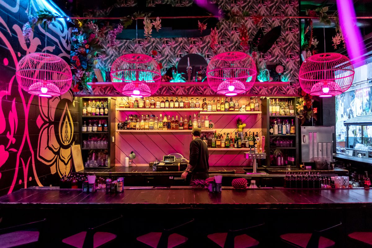A bar with multi-colored lighting and murals on the walls