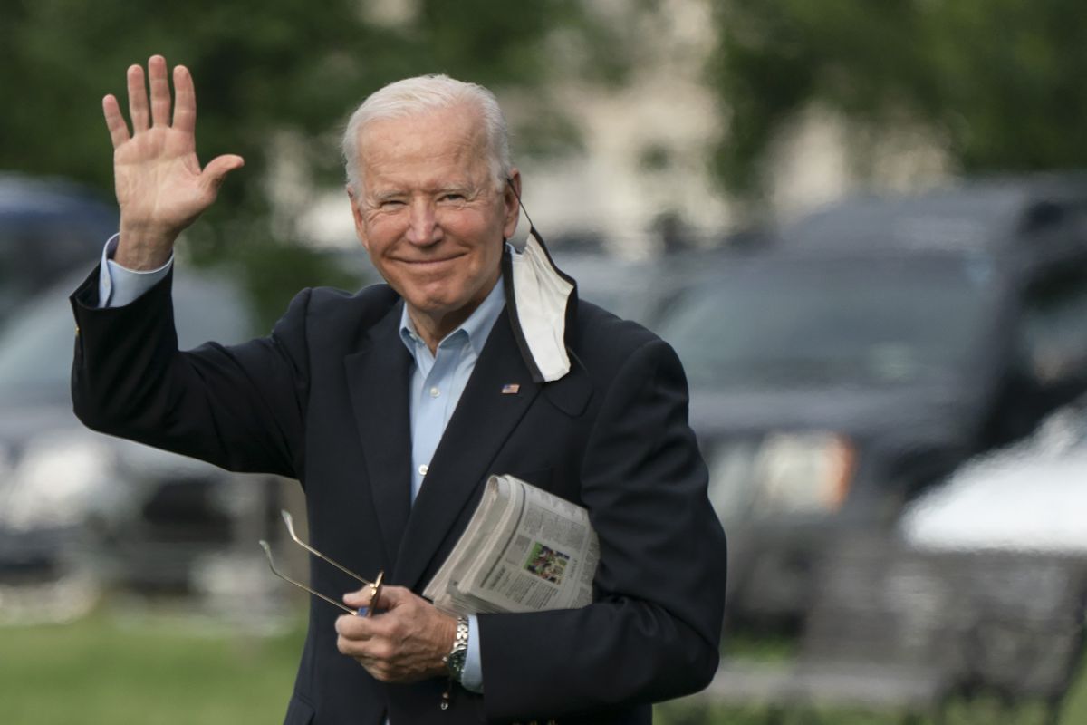President Biden waves as he crosses the White House lawn.