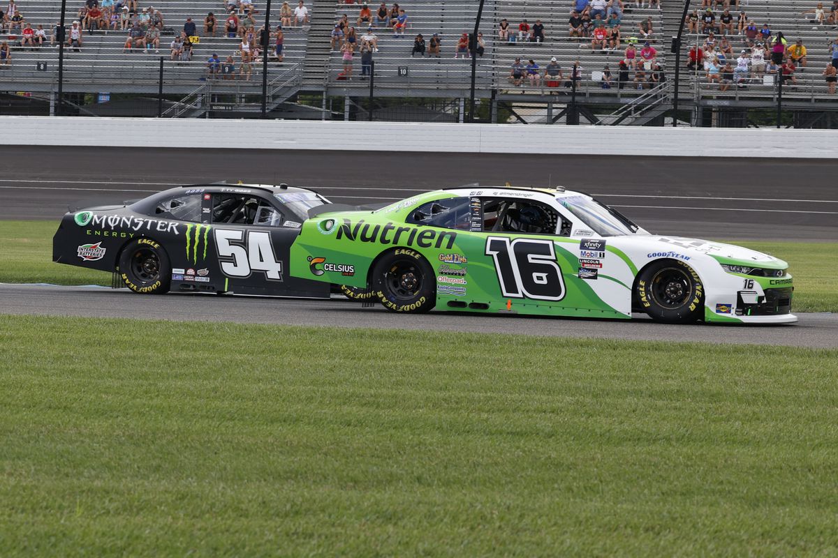 NASCAR Xfinity series driver AJ Allmendinger (16) races side by side against Ty Gibbs (54) going into turn 2 during the Pennzoil 150 at the Brickyard on July 30, 2022 at the Indianapolis Motor Speedway Road Course in Indianapolis, Indiana.