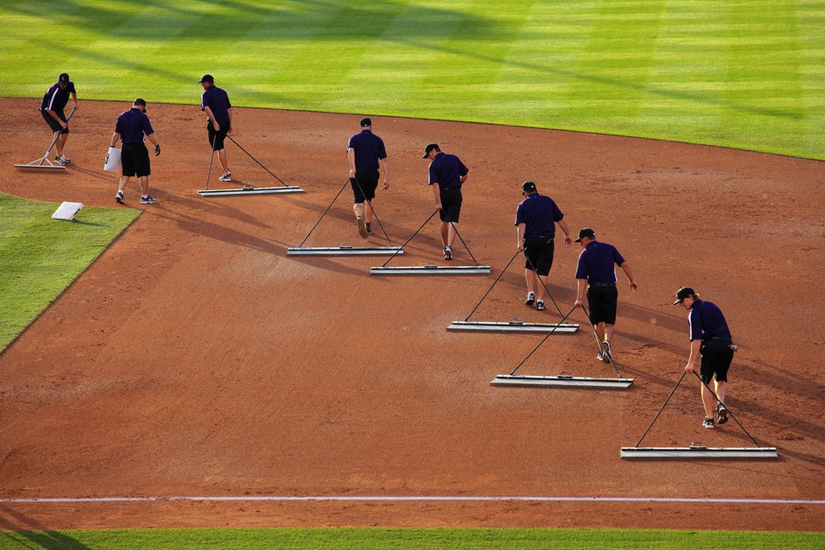 The Rockies grounds crew does their best to clear a path for Dee Gordon.