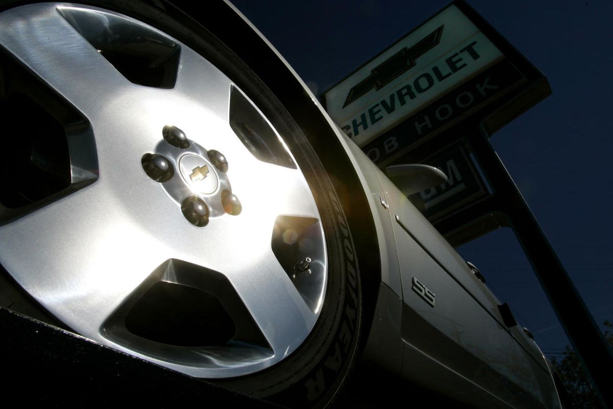 Sunlight glistens off the wheel of a new Chevrolet Impala awaiting sale on a General Motors new car lot Monday, Oct. 17, 2005, in Louisville, Ky. 