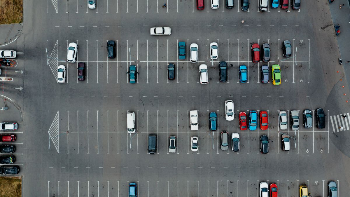 A parking lot sparsely filled with cars, seen from high above.