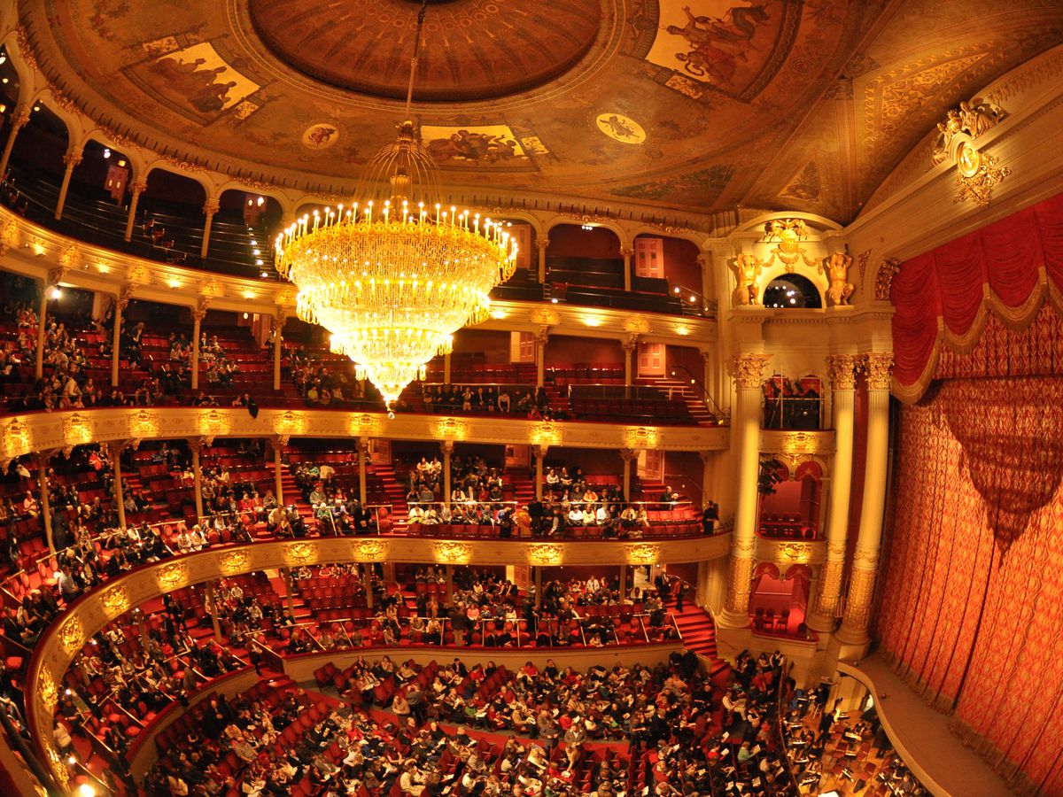 The interior of the Academy of Music in Philadelphia. There multiple balconies and many rows of seats. The stage has a curtain over it.