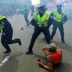 FILE - In this Monday, April 15, 2013 file photo, Bill Iffrig, 78, lies on the ground as police officers react to a second explosion at the finish line of the Boston Marathon in Boston. Iffrig, of Lake Stevens, Wash., was running his third Boston Marathon and near the finish line when he was knocked down by one of the two bomb blasts. Since Monday, Boston has experienced five days of fear, beginning with the marathon bombing attack, an intense manhunt and much uncertainty ending in the death of one suspect and the capture of the other. 