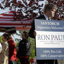 Luke Rohlfing, a supporter of presidential candidate Ron Paul, holds a sign welcoming Rick Santorum supporters outside a presidential caucus location Tuesday, April 10, 2012, in St. Charles, Mo. The original caucus held March 17 turned into chaos amid rules disputes and claims of favoritism, and adjourned with police arresting two people and no delegates selected. 