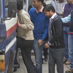 An Indian police man, in blue sweater, escorts an alleged suspect, right, who is among the seven persons in an oil espionage case, to a police van to be produced in a court from the Delhi Crime Branch unit, in New Delhi, India, Friday, Feb. 20, 2015. Police have arrested seven people for allegedly stealing classified documents from the Indian government and selling them to energy companies, a top police officer said Friday. 