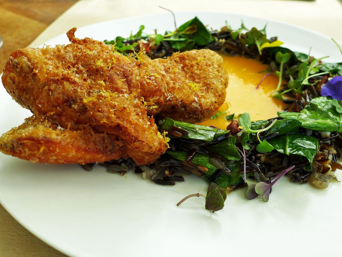 Fancy fried chicken in a yellow habanero sauce surrounded by a ring of leaves