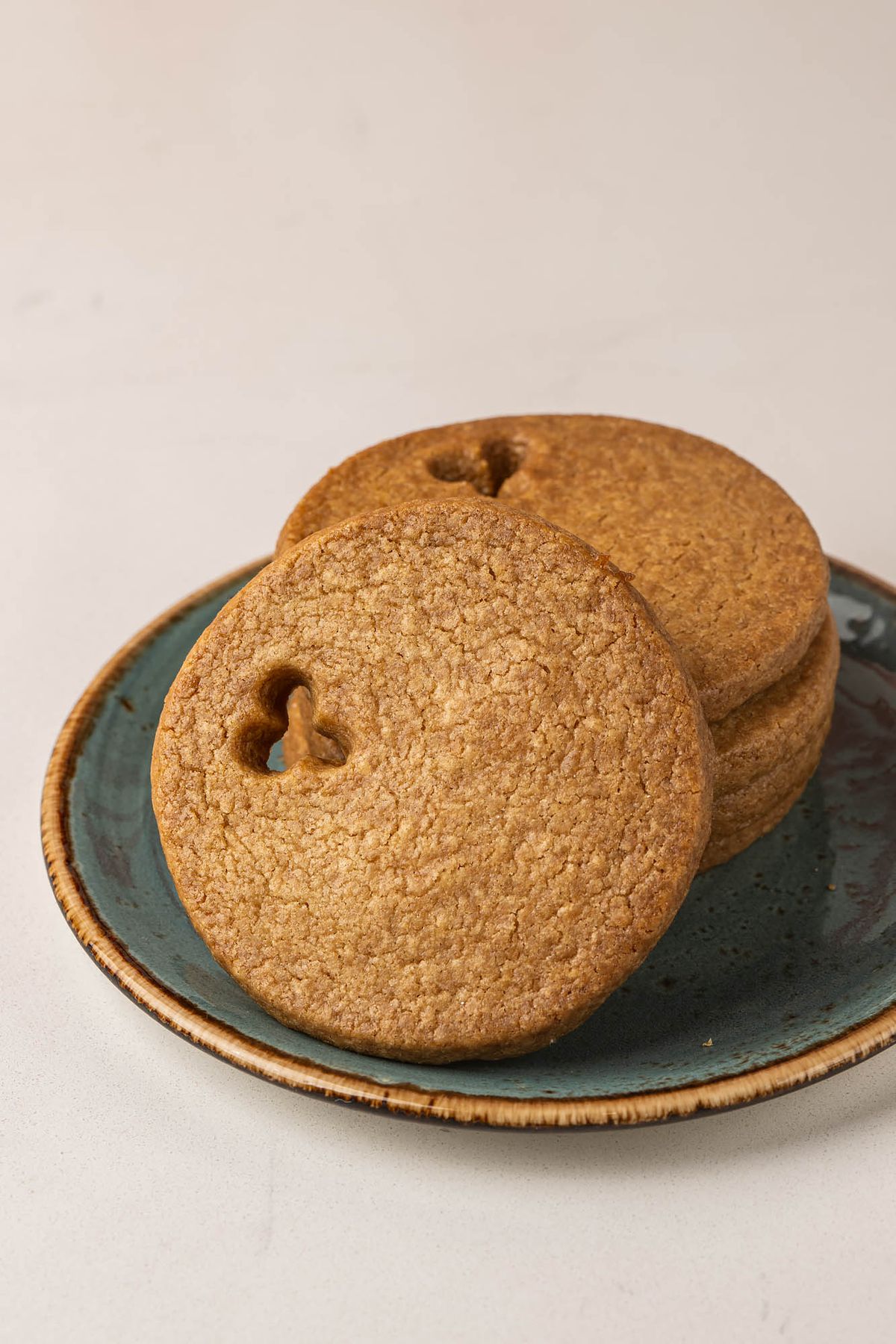 Circular dark brown cookies with small holes cut out on a green ceramic plate at an LA bakery.