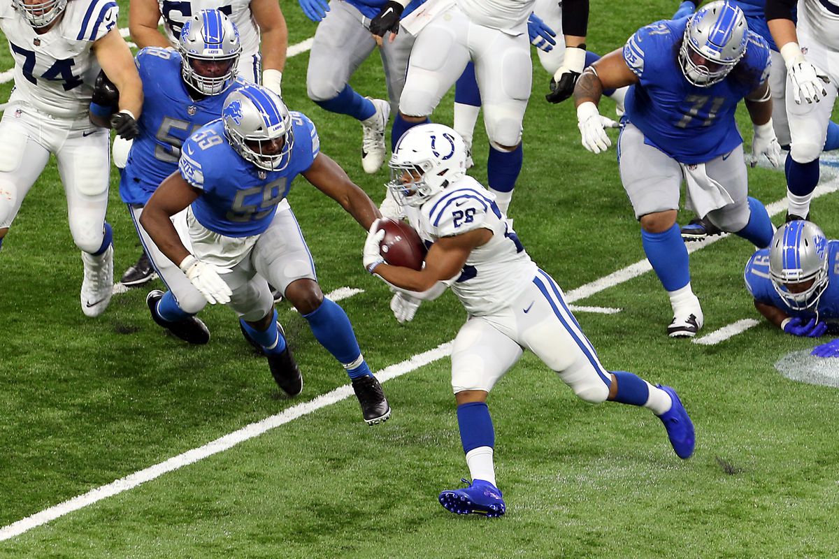 Indianapolis Colts running back Jonathan Taylor (28) carries the ball under the pressure of Detroit Lions defense during the first half of an NFL football game against the Detroit Lions in Detroit, Michigan USA, on Sunday, November 1, 2020.