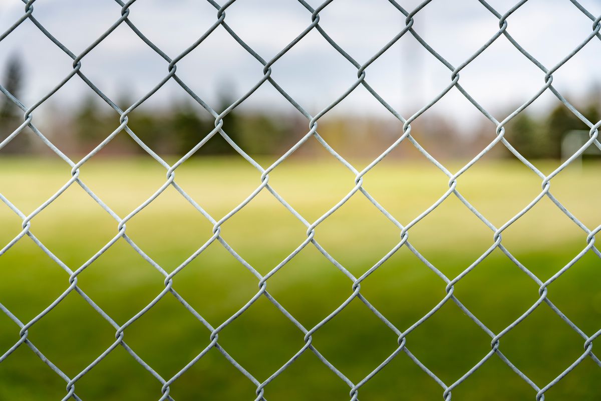 Looking through a chain link fence onto an open field. 