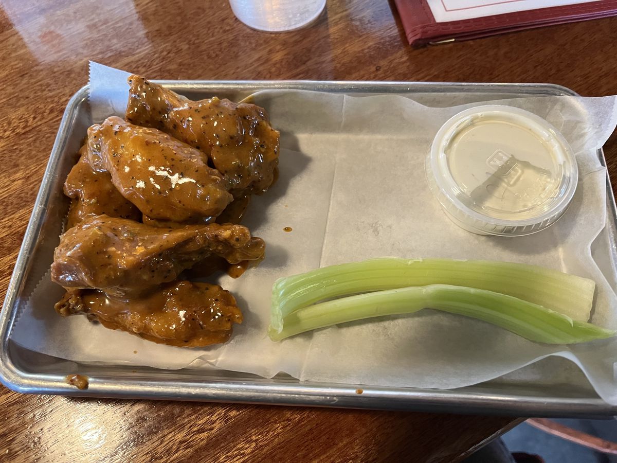 A plate of wings with blue cheese sauce and celery.