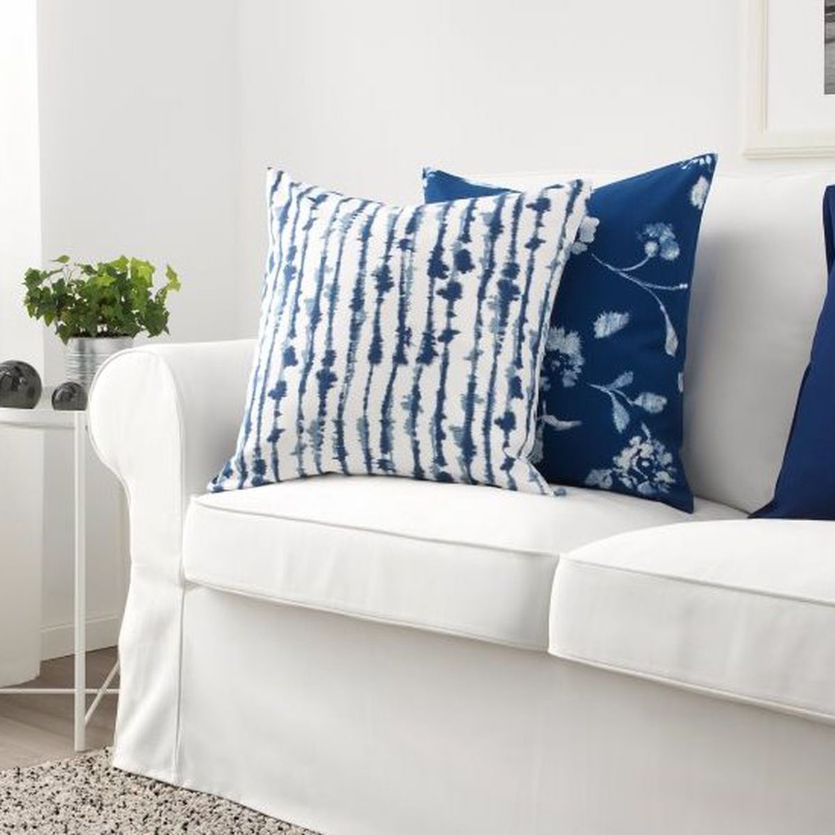 Blue and white pillows sit on a white couch. 