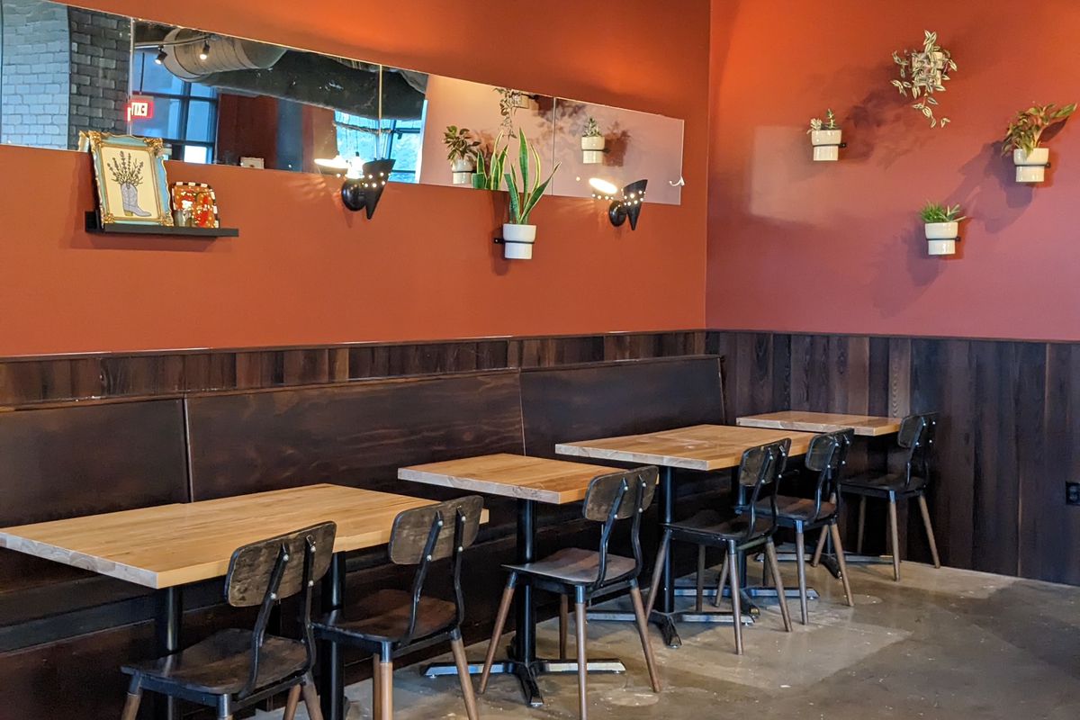 The interior of a restaurant with burnt orange walls and wood furniture.