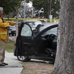 An investigator checks a car damaged by a bullet at the intersection of Kansas and Yorkshire about a mile northeast of Santa Monica College in Santa Monica, Calif. on Friday, June 7, 2013. 