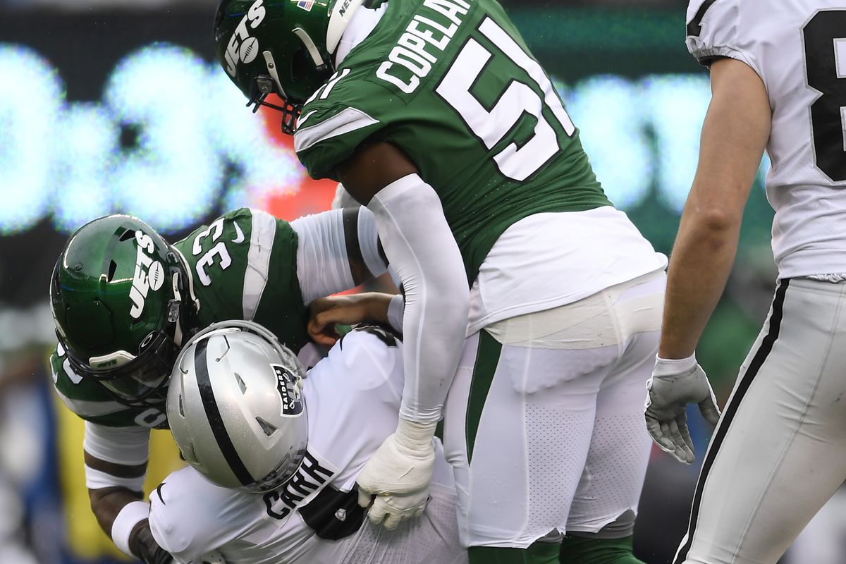 Strong safety Jamal Adams and outside linebacker Brandon Copeland of the New York Jets sack quarterback Derek Carr of the Oakland Raiders during the first half of the game at MetLife Stadium on November 24, 2019 in East Rutherford, New Jersey.