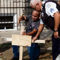A Chicago Police officer helps construct a memorial Sunday morning. | Matthew Hendrickson/Sun-Times