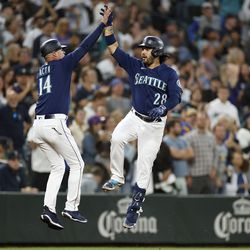 AUGUST 27: Eugenio Suarez #28 of the Seattle Mariners reacts with third base coach Manny Acta #14 after his home run during the second inning against the Cleveland Guardians at T-Mobile Park on August 27, 2022 in Seattle, Washington.