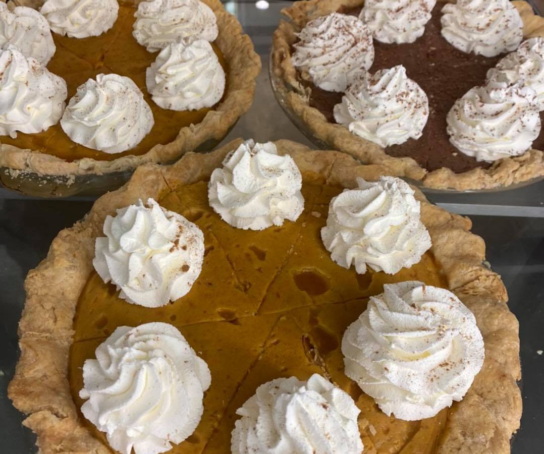 Three pumpkin pies with whipped cream