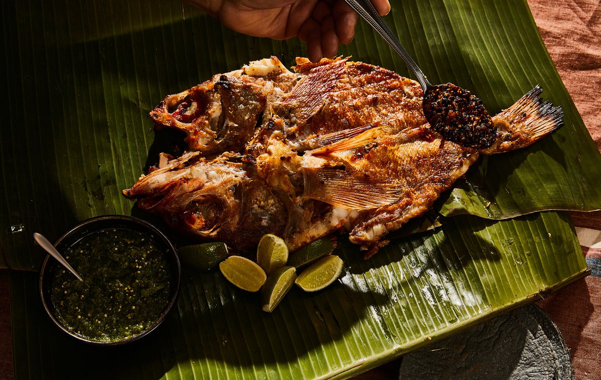 A fish wrapped in banana leaves garnished with limes.