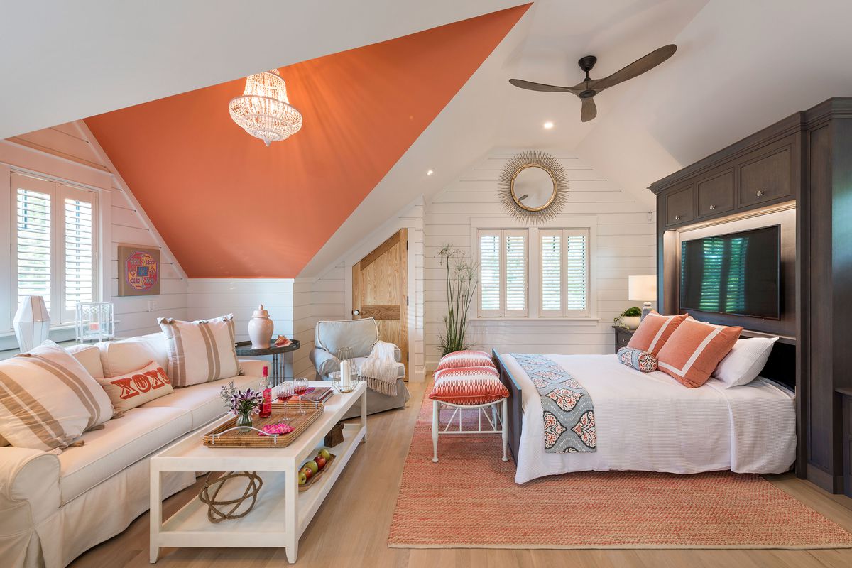 A guest room with a murphy bed, shiplap walls and orange accents. 