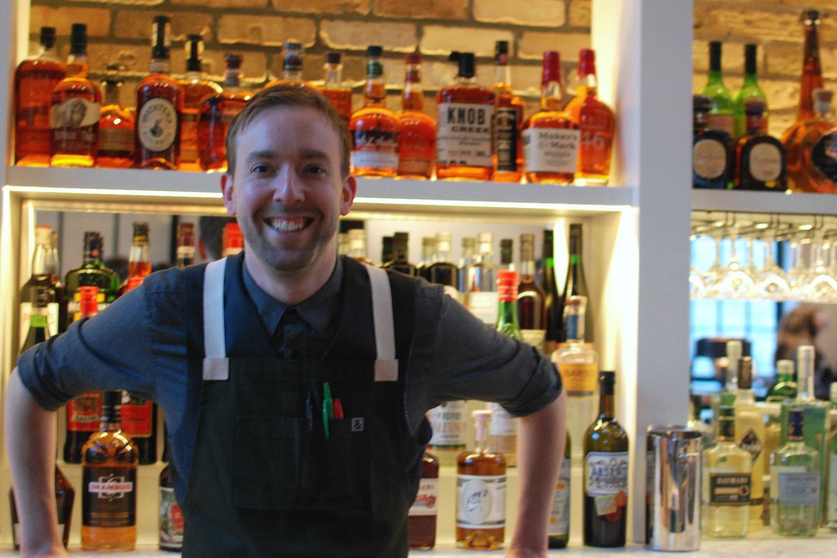 Robb Jones in an apron smiling behind a bar